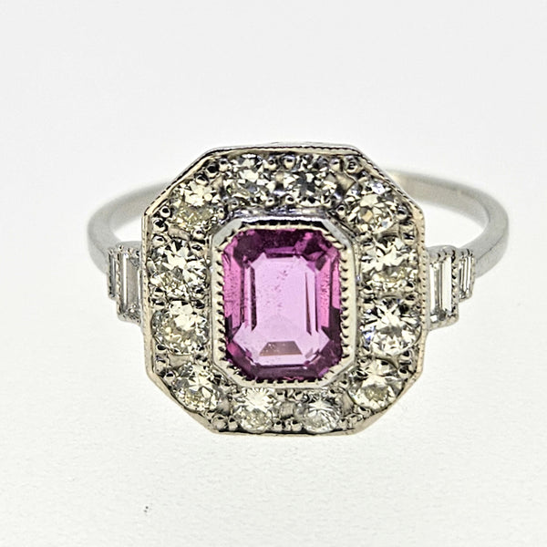 An emerald cut pink sapphire and diamond cluster ring in platinum