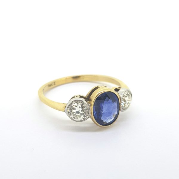 Sapphire and Diamond Three Stone Ring; featuring a 1.26 carat oval faceted sapphire flanked by 0.67cts brilliant cut diamonds, in 18ct yellow gold