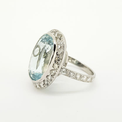 An aquamarine and diamond large oval cluster ring in white metal, against a white background