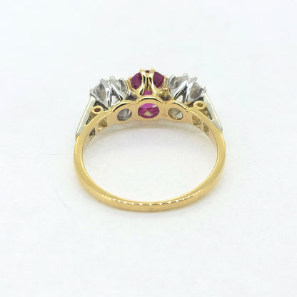 A three stone ruby and diamond ring in yellow and white gold, against a white background