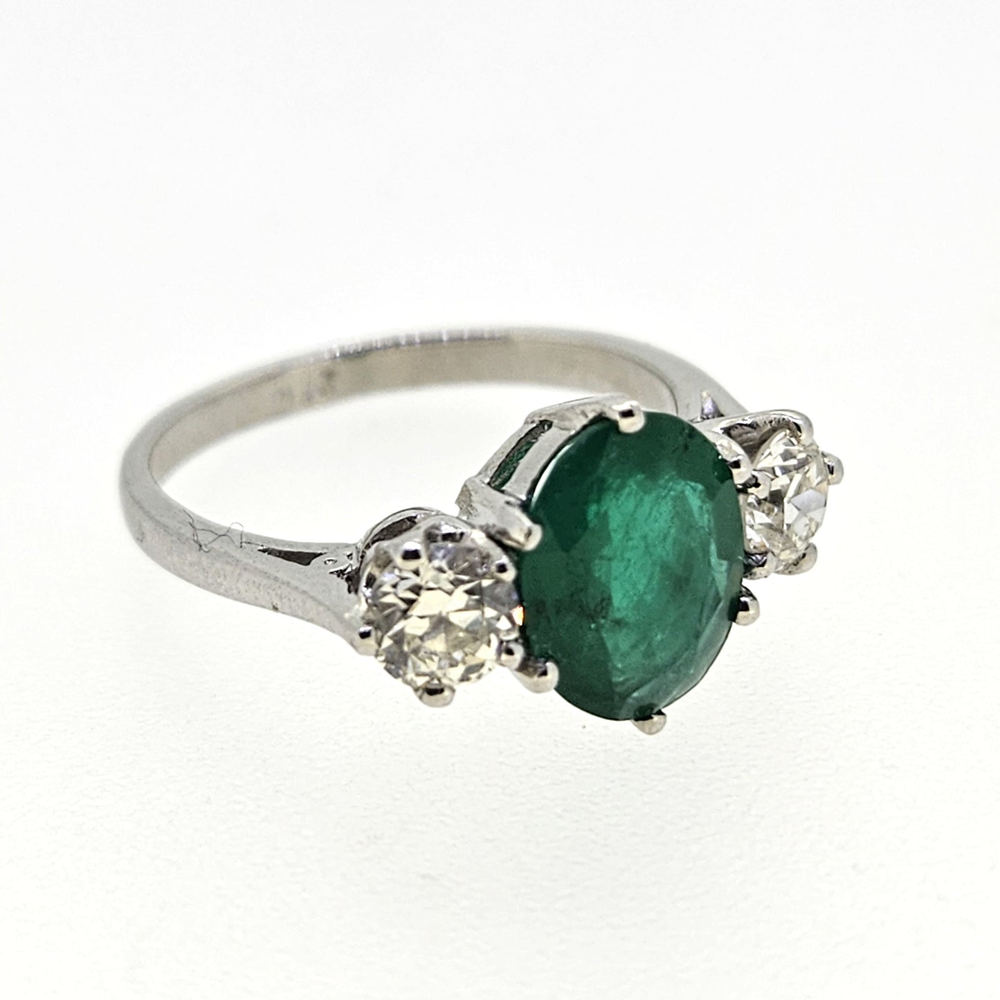 A three stone oval emerald and round diamond ring in platinum