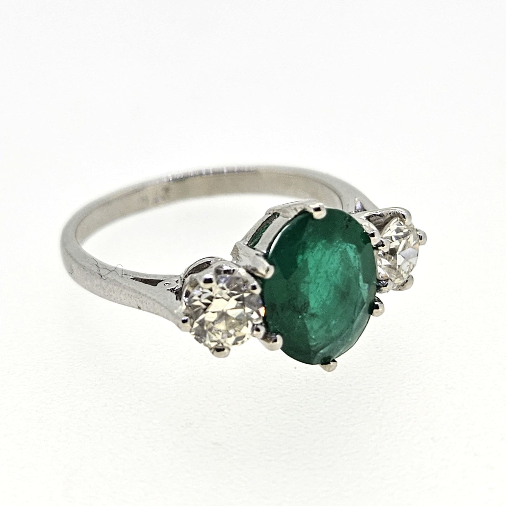 A three stone oval emerald and round diamond ring in platinum