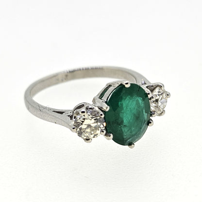 A three stone oval emerald and round diamond ring in platinum