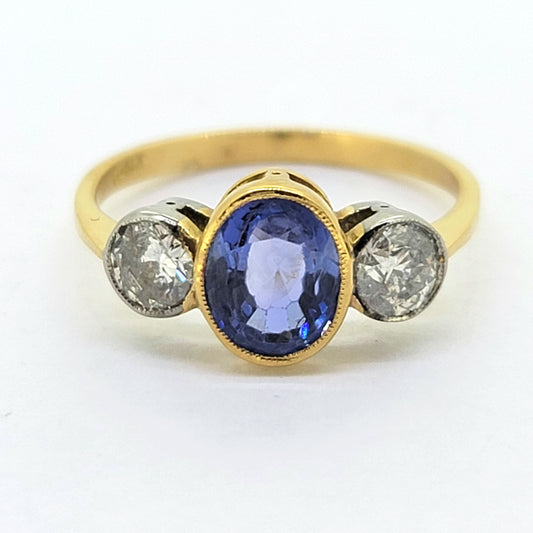 A three stone sapphire and diamond ring in yellow and white gold, on a white background