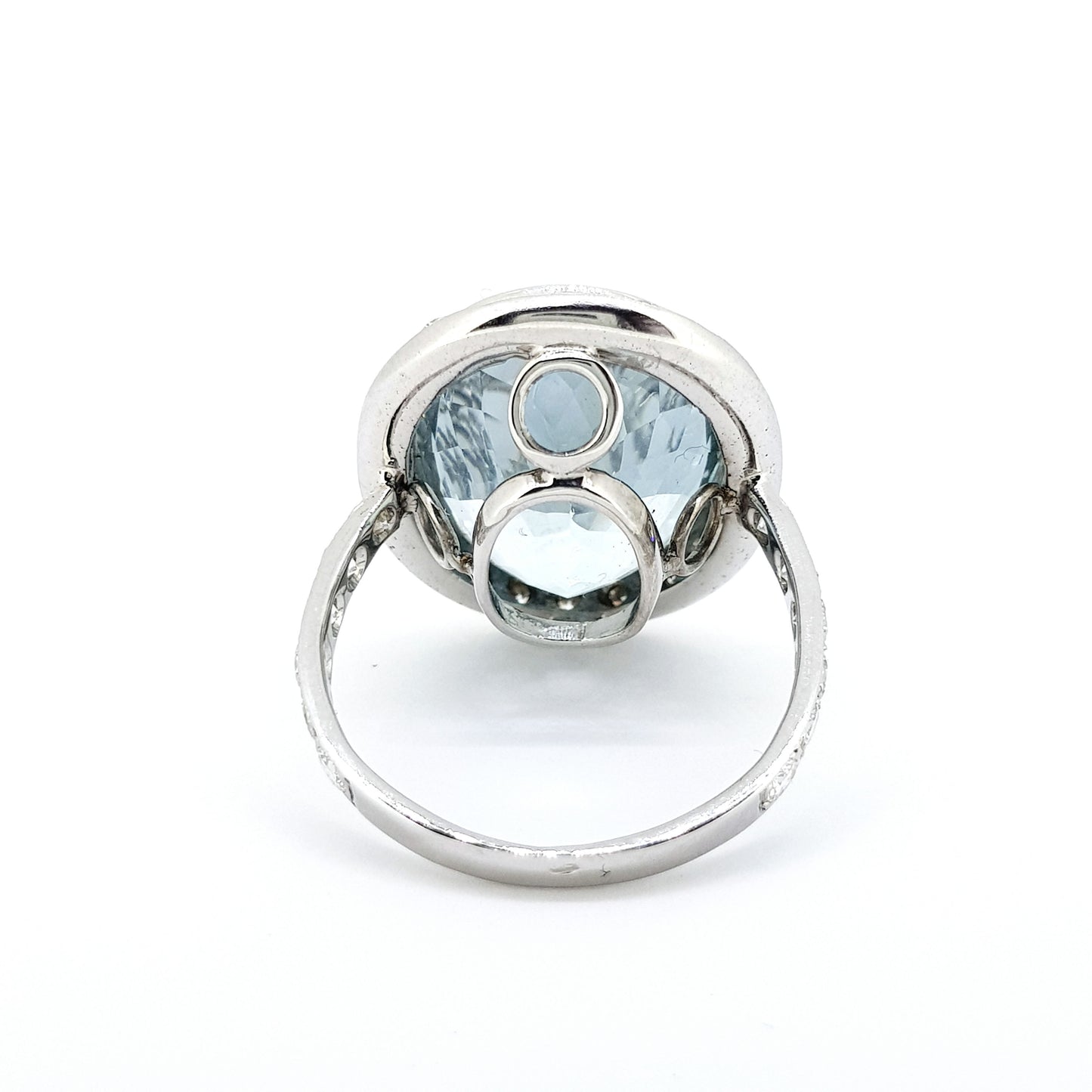 An aquamarine and diamond large oval cluster ring in white metal, against a white background