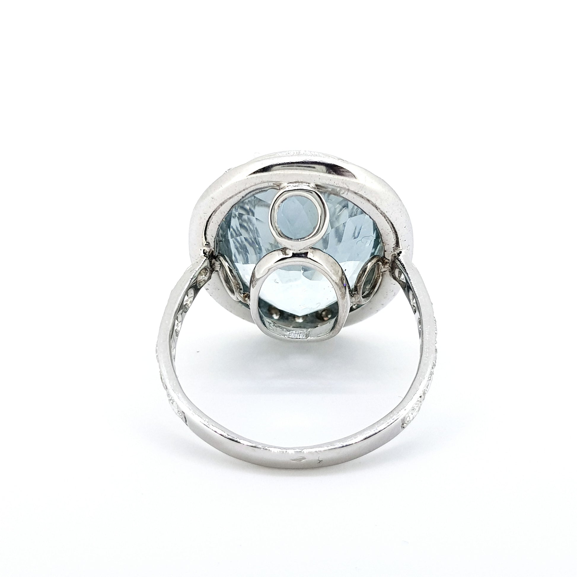An aquamarine and diamond large oval cluster ring in white metal, against a white background