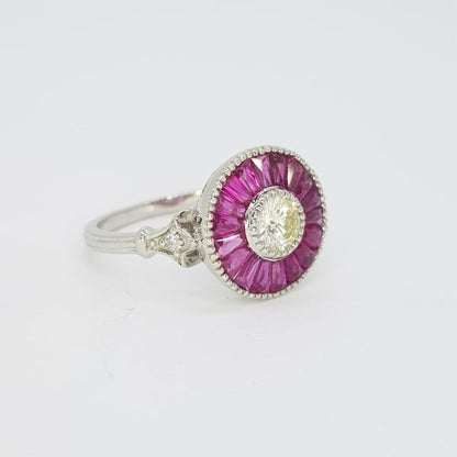 Ruby and Diamond Cluster Target Ring; featuring a central round brilliant-cut diamond surrounded by calibre-cut rubies, in platinum with millegrain edging