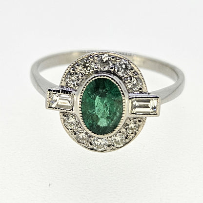 An oval emerald and diamond cluster ring in platinum