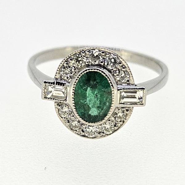 An oval emerald and diamond cluster ring in platinum