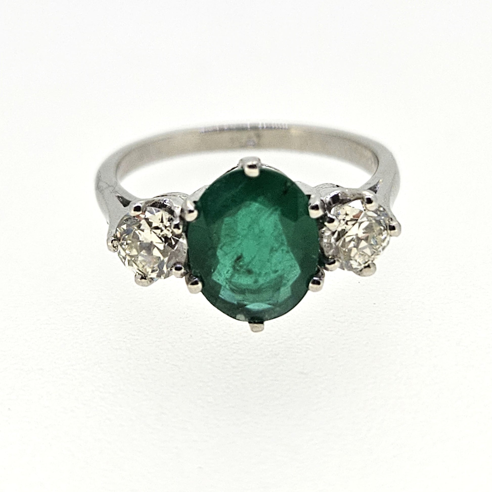 A three stone oval emerald and round diamond ring in platinum