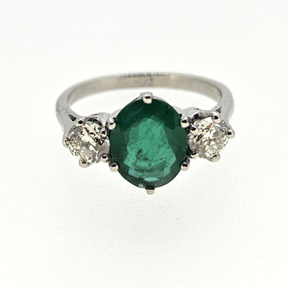 A three stone oval emerald and round diamond ring in platinum