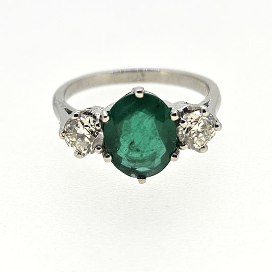 A three stone oval emerald and round diamond ring in platinum