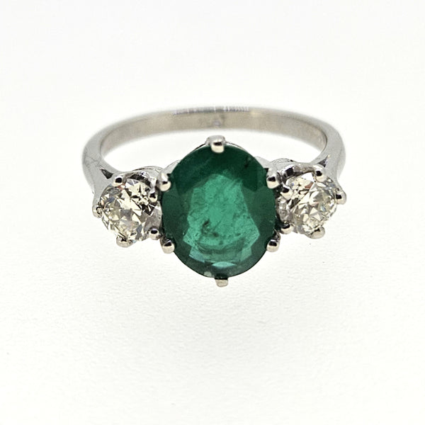 A three stone oval emerald and round diamond ring in platinum