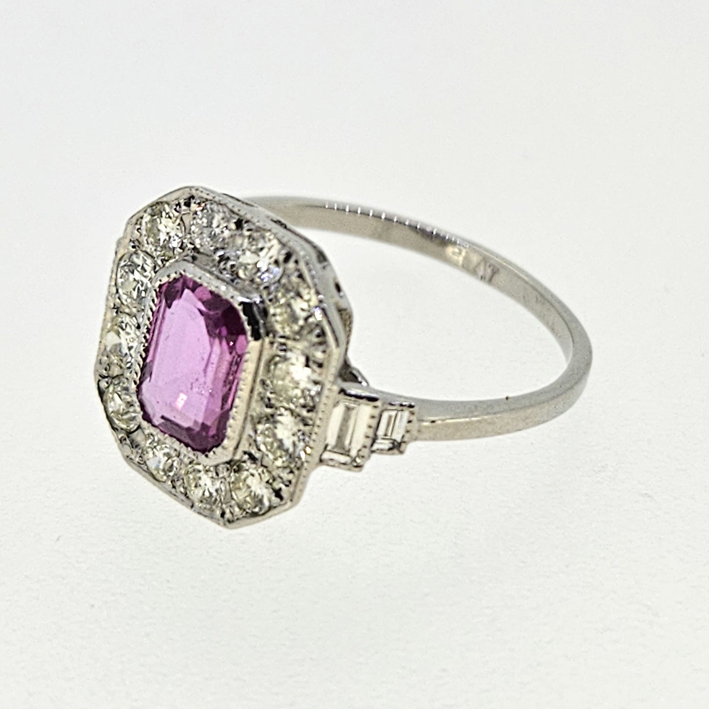 An emerald cut pink sapphire and diamond cluster ring in platinum