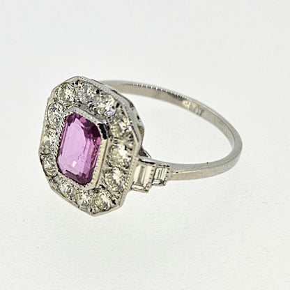 An emerald cut pink sapphire and diamond cluster ring in platinum