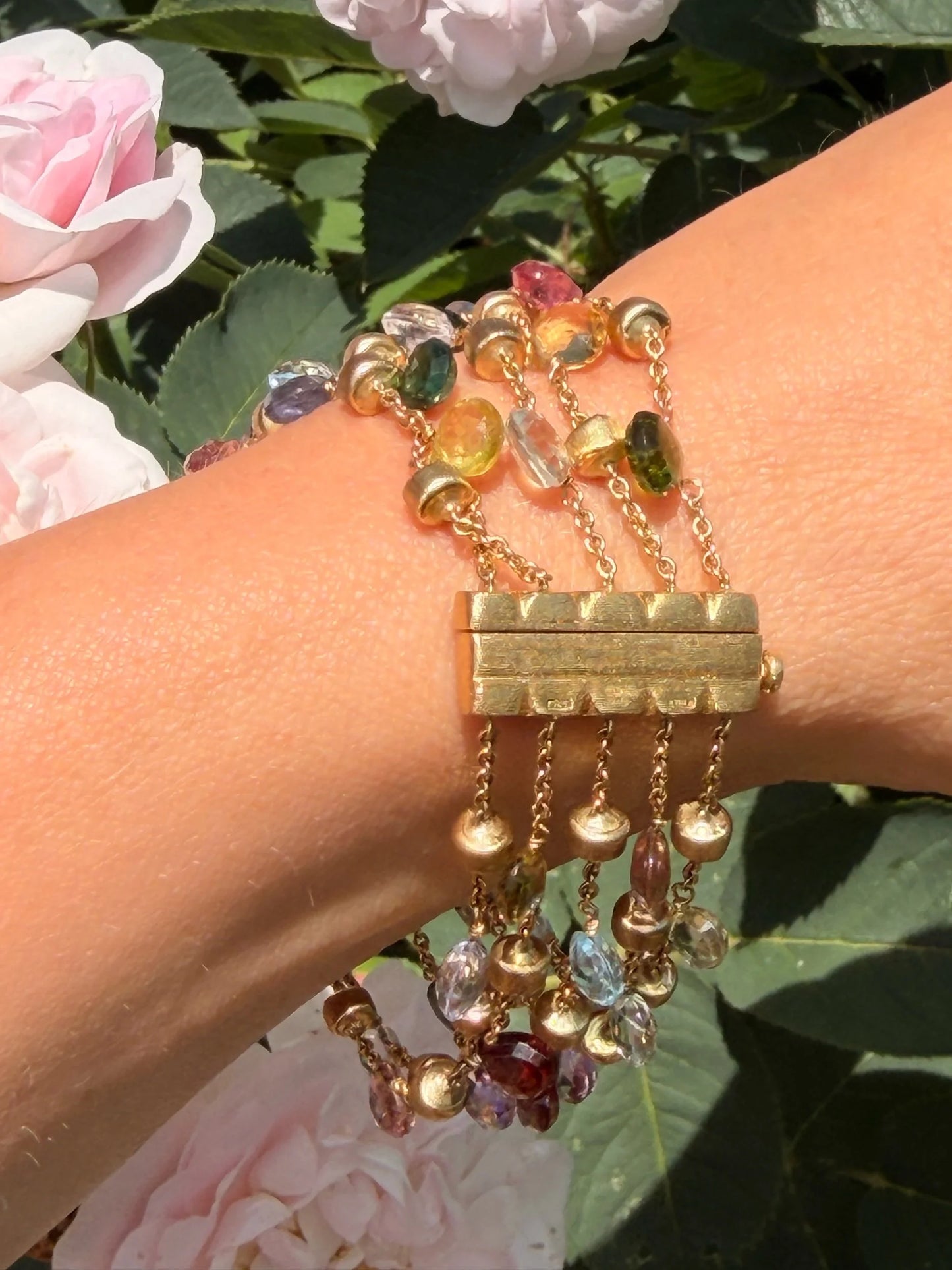 A yellow gold five row multi-gemstone bracelet, modelled on a wrist