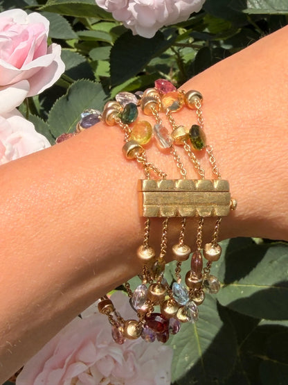 A yellow gold five row multi-gemstone bracelet, modelled on a wrist