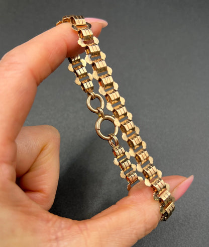 A rose gold fancy link bracelet, held in a hand