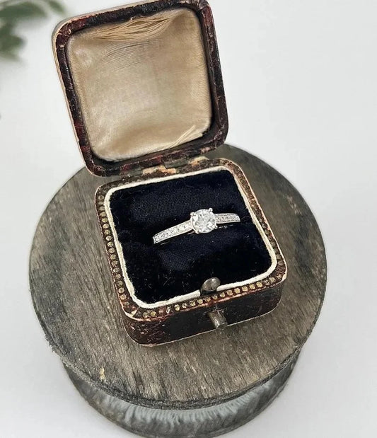 A white gold brilliant cut diamond engagement ring with diamond set shoulders, in a ring box