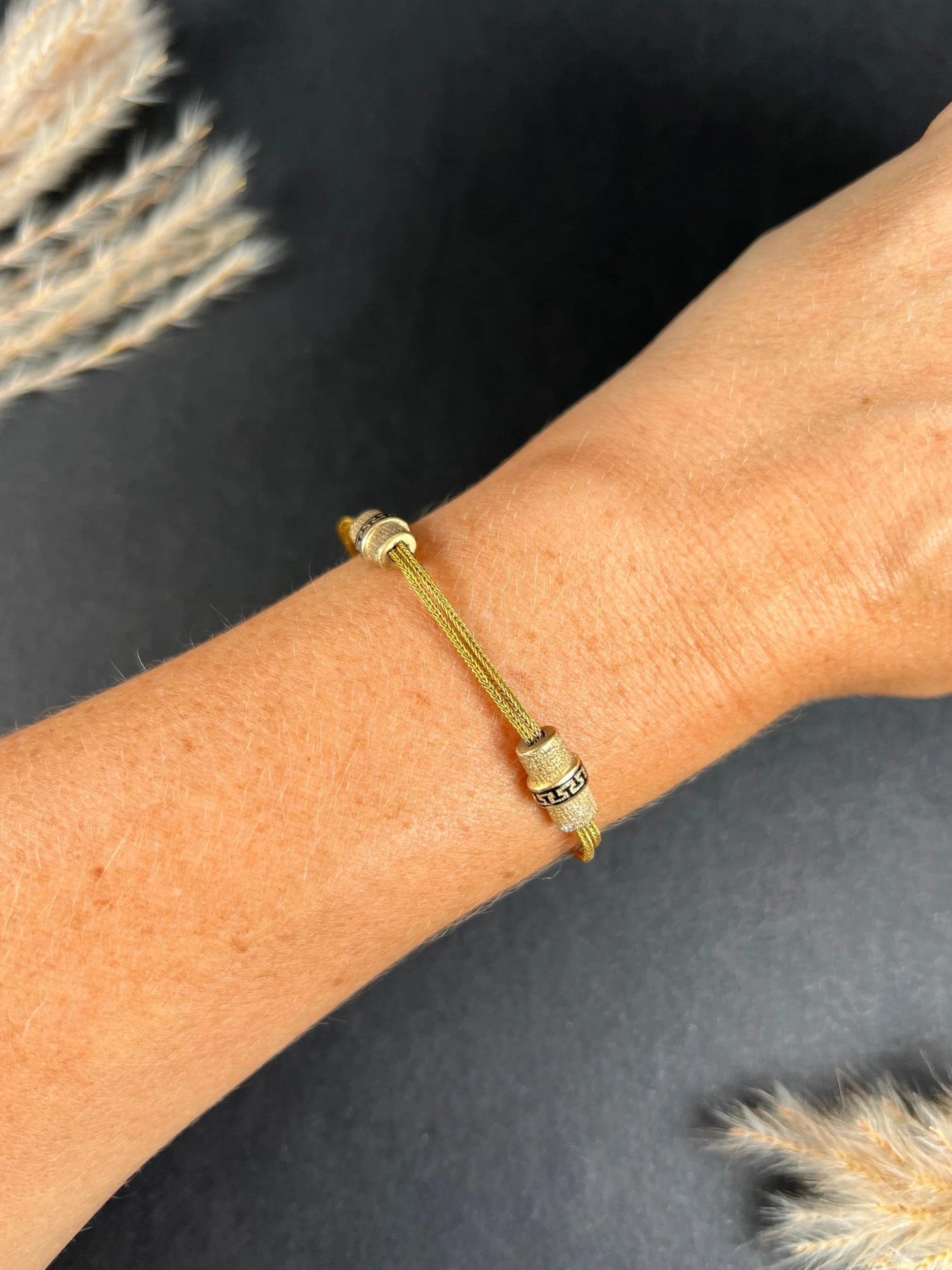 A yellow gold double row bracelet with black enamel tubular beads, modelled on a wrist