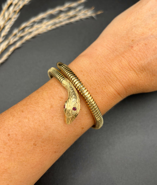 A yellow gold snake bracelet with ruby eyes, modelled on a wrist