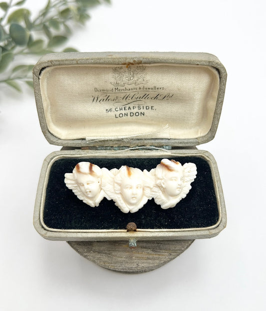 A triple cherub carved antique brooch, in an antique box