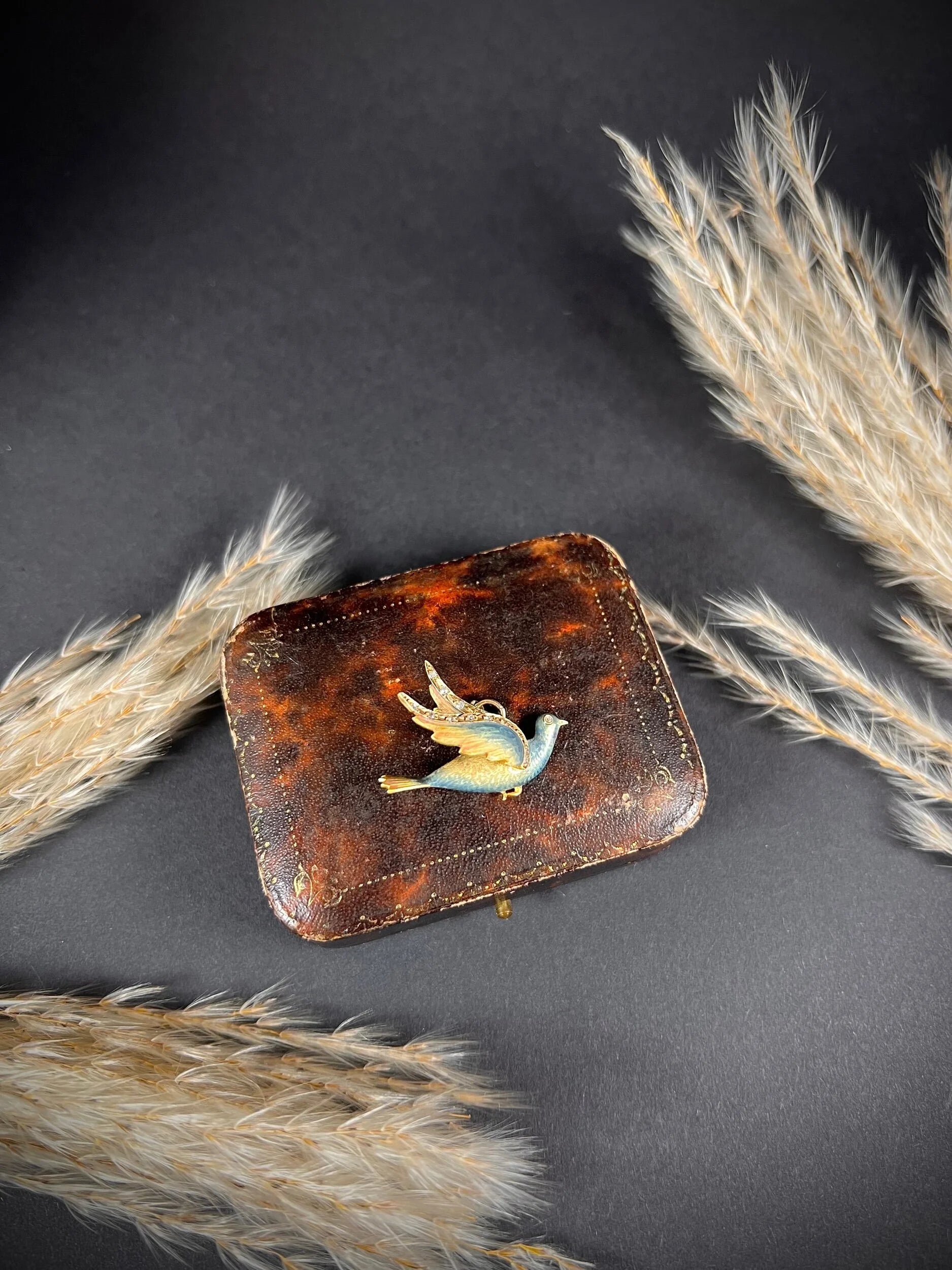 An enamel and diamond dove bird pendant, on an antique box