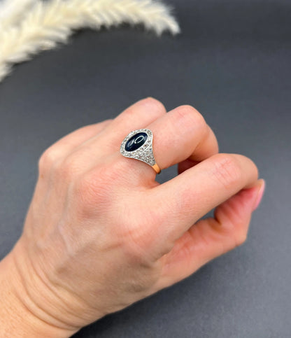 An oval cabochon sapphire and diamond fancy cluster ring in yellow and white gold, modelled on a hand