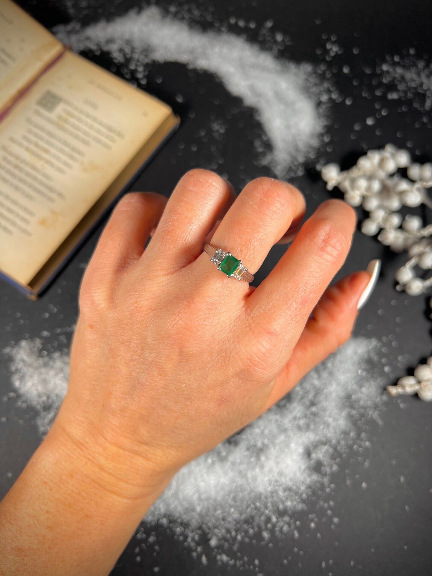 A three stone emerald and diamond ring in platinum, modelled on a hand