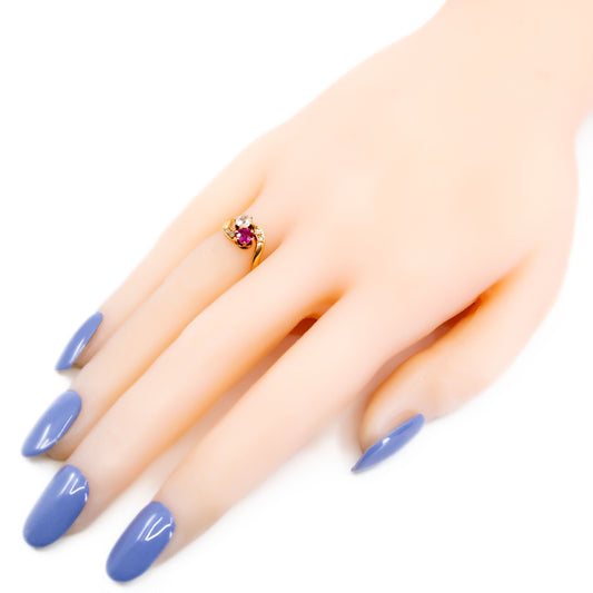 A two stone crossover ring in yellow gold with a ruby and diamonds, modelled on a hand