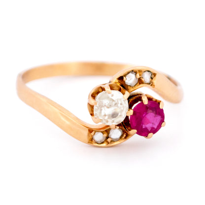 A two stone crossover ring in yellow gold with a ruby and diamonds