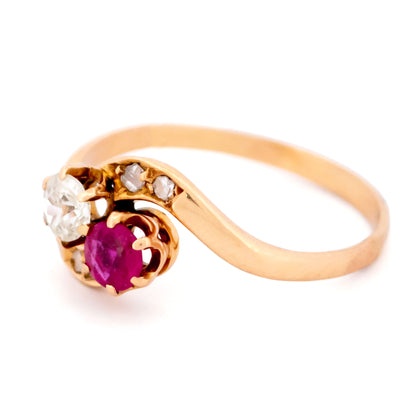A two stone crossover ring in yellow gold with a ruby and diamonds