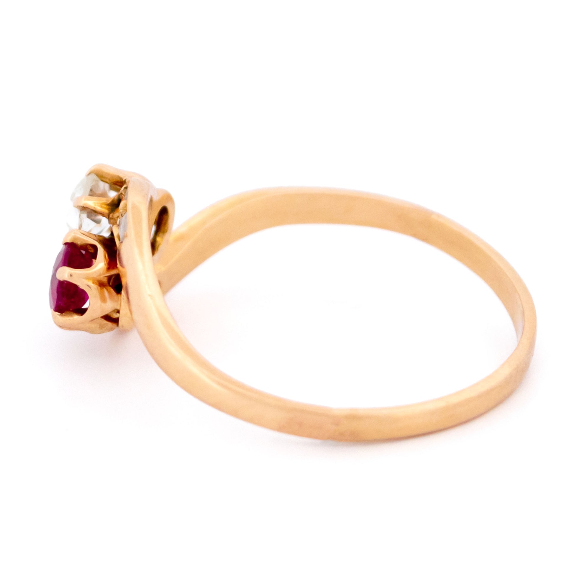 A two stone crossover ring in yellow gold with a ruby and diamonds