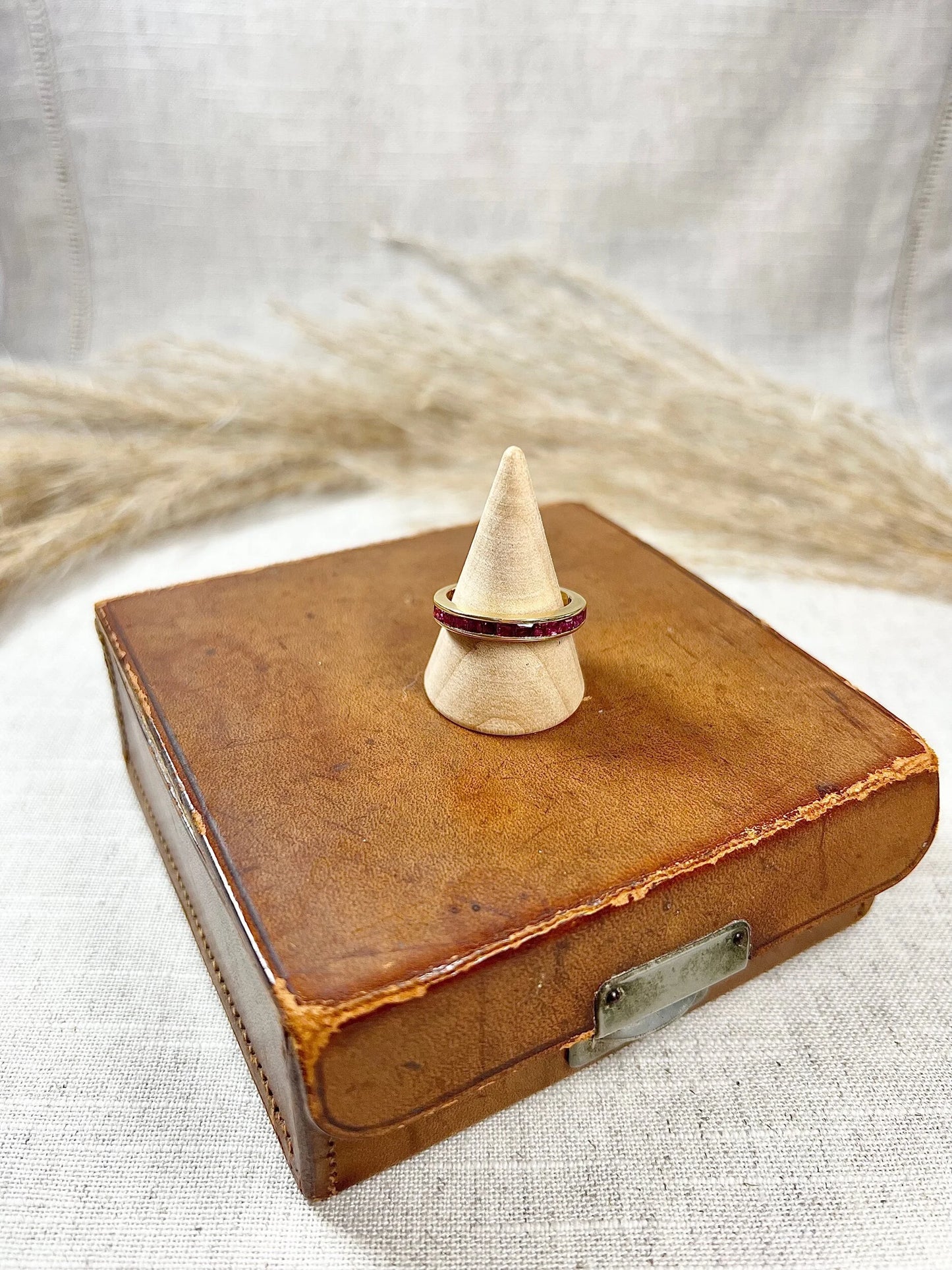 A yellow gold ruby channel set eternity band, on a wooden ring cone