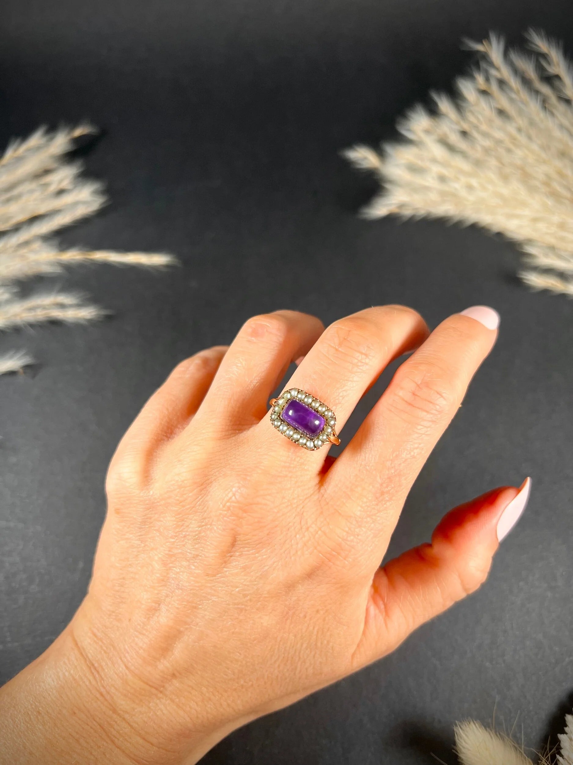 A cabochon amethyst and pearl halo cluster ring in gold, modelled on a hand