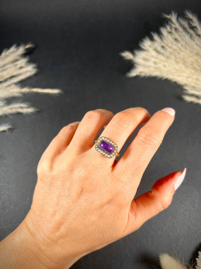 A cabochon amethyst and pearl halo cluster ring in gold, modelled on a hand