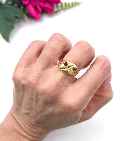 A yellow gold double headed snake ring with a ruby and a diamond, modelled on a hand
