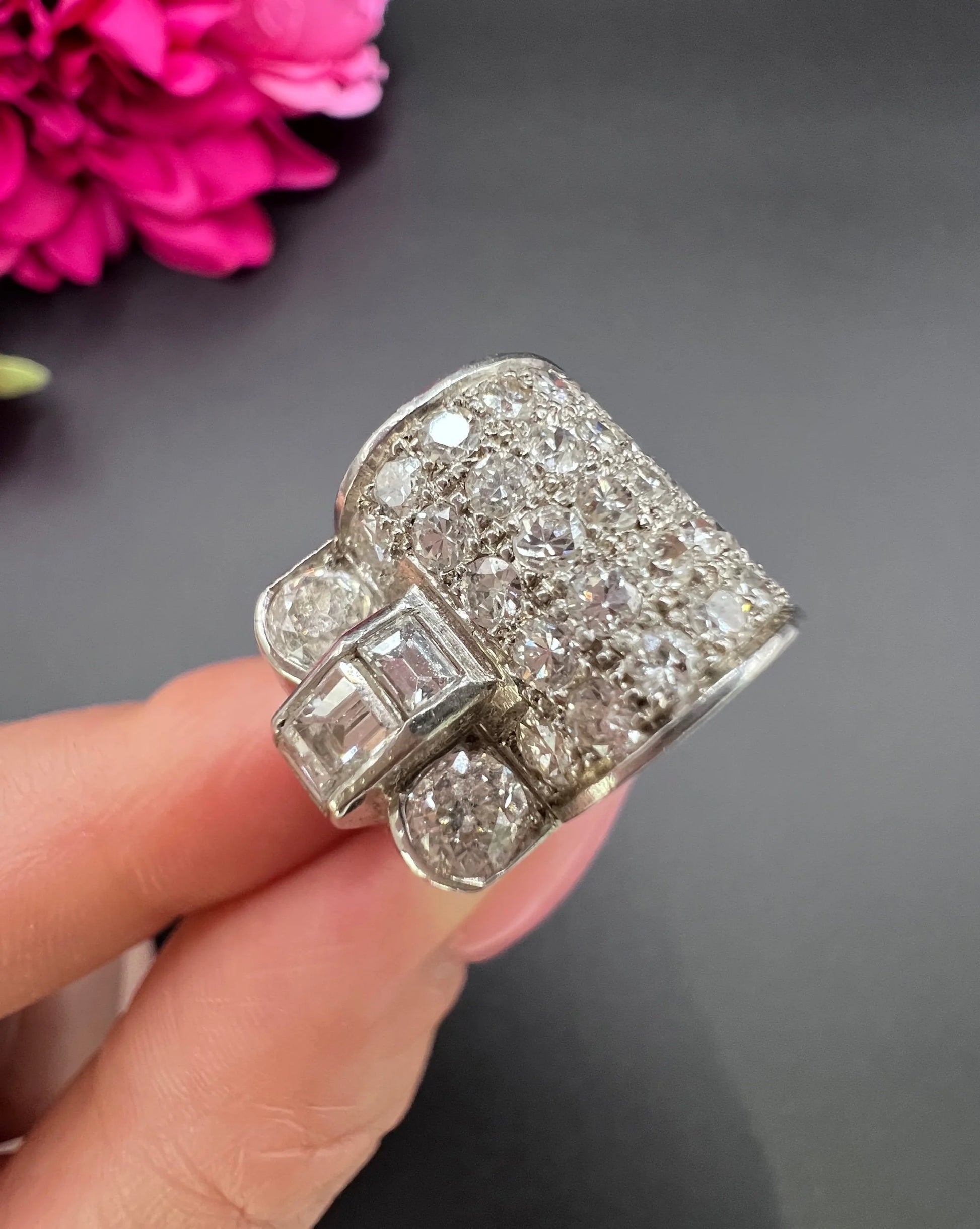 A round and square diamond tank style cocktail ring in platinum, held in a hand