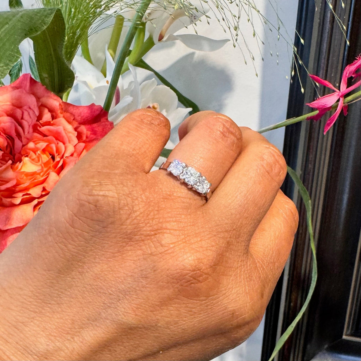 A three stone round diamond ring claw set in platinum, modelled on a hand