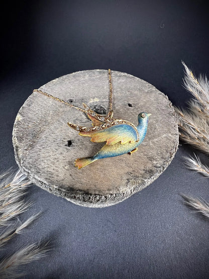 An enamel and diamond dove bird pendant, with a chain, on a wooden spool