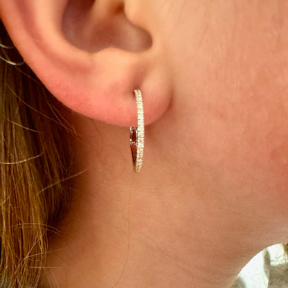 A white gold diamond hoop earring, modelled in an ear