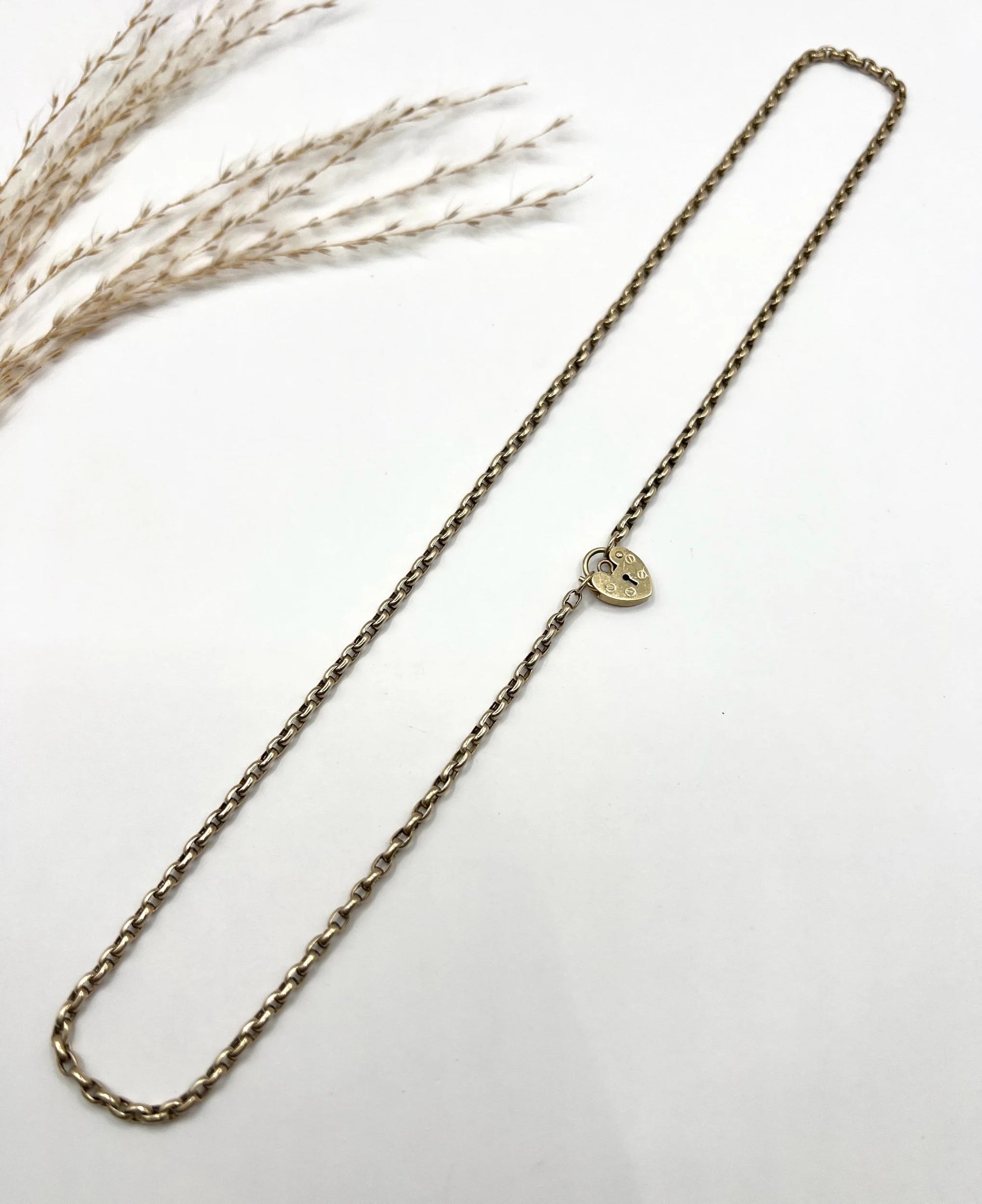 A gold belcher link chain with a heart shaped padlock clasp pendant