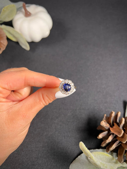 A round sapphire and diamond cluster ring, held in a hand