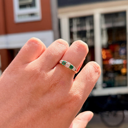 A five stone old cut emerald and diamond graduated ring in yellow gold, modelled on a hand
