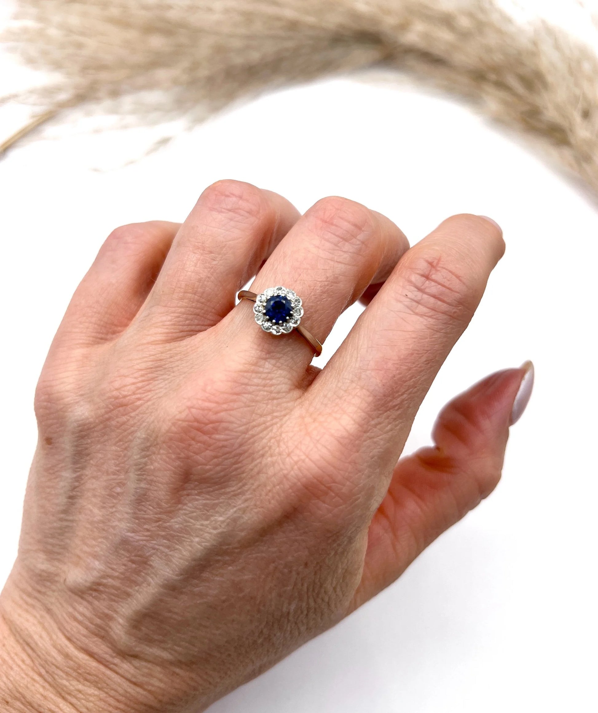 A sapphire and diamond flower cluster ring in yellow gold and platinum, modelled on a hand