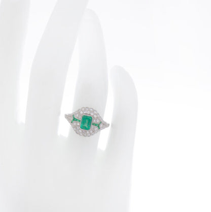 Art Deco Style Emerald, Diamond and Platinum Cluster Dress Ring; central emerald-cut emerald surrounded by brilliant-cut diamonds and accented by calibre-cut emerald set shoulders. Circa 1980s