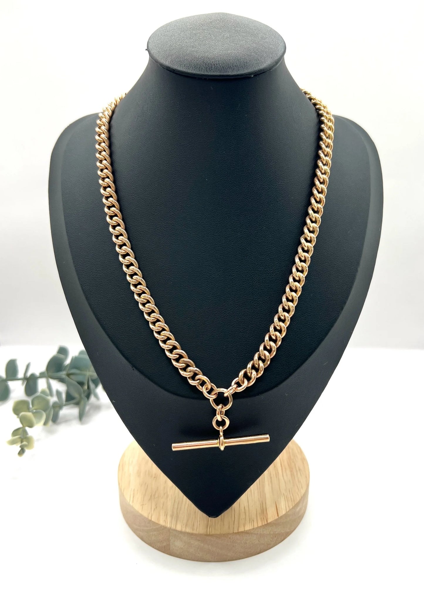 A rose gold curb link Albert chain on a black jewellery bust
