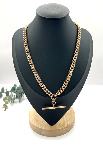 A rose gold curb link Albert chain on a black jewellery bust
