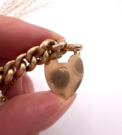 A close-up of a heart shaped padlock with a stamp, held in a hand
