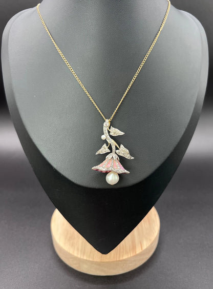 A pink enamel, diamond and pearl flower pendant in gold and silver, with a chain, modelled on a black jewellery bust